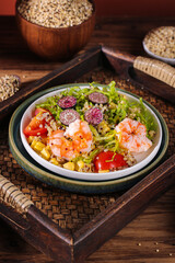 Healthy quinoa salad bowl with shrimp and fresh vegetables on rustic wooden background