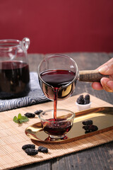 Pouring Mulberry Tea from Glass Teapot with Dried Fruit and Mint on Bamboo Tray - Herbal Drink Preparation