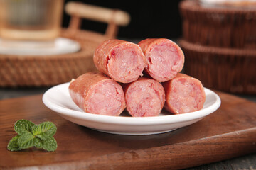 Raw Sausages on White Plate with Mint Garnish Ready for Grilling on Wooden Board