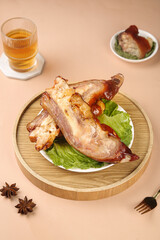 Golden marinated pork knuckle with spicy glaze on wooden serving plate - delicious Asian cuisine meal