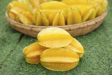Fresh Star Fruit Slices and Whole Starfruit in Wicker Basket on Green Surface