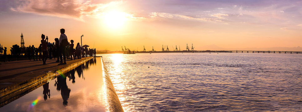 Tourists enjoying the sunset in the port area, a tourist attraction in the city of Rio de Janeiro, behind the Museum of Tomorrow with a view of the Rio-Niter&oacute;i bridge and reflecting pool.