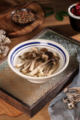 Dried shiitake mushrooms in ceramic bowl with spices on rustic wooden table for healthy cooking