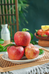 Fresh Red Apples with Leaves on White Plate in Rustic Kitchen Setting