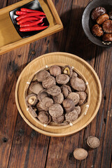 Fresh dried shiitake mushrooms in bamboo basket on wooden background with Asian cooking ingredients