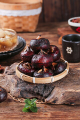 Fresh Roasted Chestnuts in Bamboo Basket on Rustic Wood Farm Kitchen Table