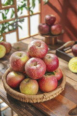 Fresh Red Apples in Wicker Basket on Rustic Wooden Kitchen Table with Natural Light