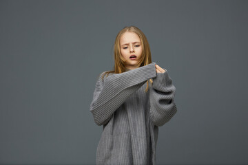 A young model with light brown hair dressed in an oversized gray sweater, expressing a contemplative mood against a soft gray background Perfect for themes of fashion and self reflection