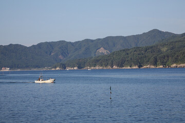 静かな入り江を走る漁船