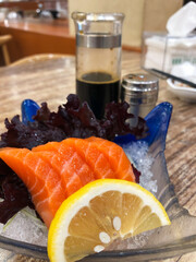 Fresh sashimi served with Japanese soy sauce and garnished with lemon slices and lettuce leaves, sashimi dish at a Japanese restaurant