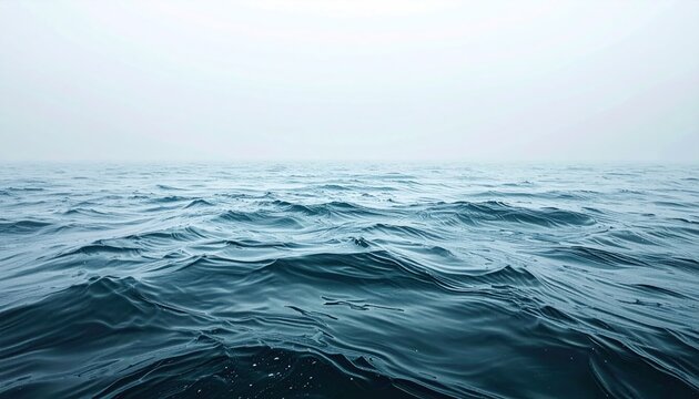 A tranquil expanse of deep blue water gently ripples under a thick blanket of fog, creating a calming, minimalist ocean scene - Powered by Adobe
