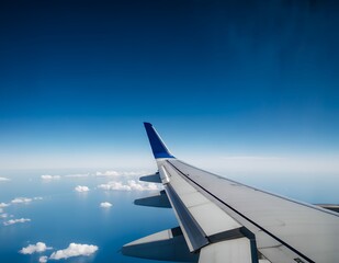 Fototapeta premium Airplane wing against a clear blue sky and ocean view, creating a serene travel atmosphere.