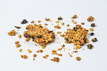Two Granola bars with almonds, oats, and dried cranberries, isolated on a white background. Close up view. clipping path. piece. Flat lay. broken. scattered. crumbs. cracked.