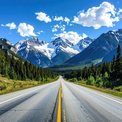 Naklejka premium Asphalt roadway stretches through a lush valley toward majestic, snow-capped mountains under a vibrant blue sky dotted with puffy white clouds