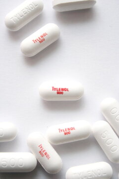 WA USA , 09 24 2025 -  White Tylenol 500mg caplets scattered on a white surface, focusing on a single pill. Pain relief concept.