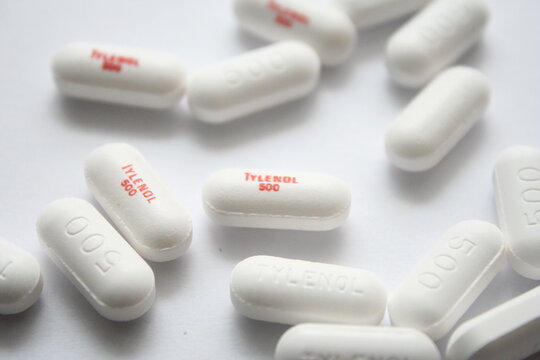 WA USA , 09 24 2025 -  White Tylenol 500mg caplets scattered on a white surface, focusing on a single pill. Pain relief concept.