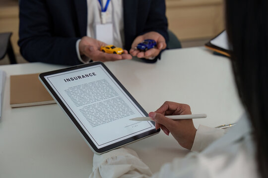 Insurance Consultation. Client reviewing policy details on tablet with agent.