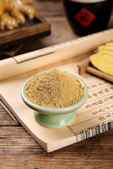 Ginger powder spice in bowl with Asian cooking ingredients on wooden kitchen counter
