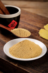 Fresh Ginger Powder Spice in Bowl and Wooden Spoon with Traditional Asian Cooking Ingredients on Rustic Wood Table