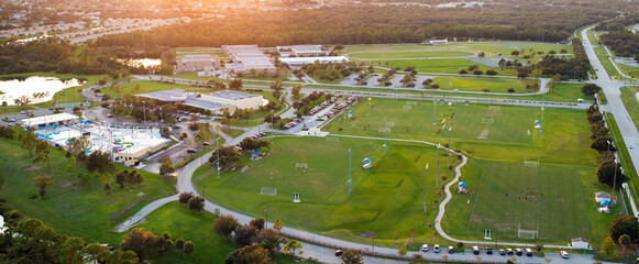 Public sports stadium with school kids playing football game at sunset. Active way of life concept