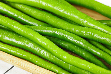 Freshly picked green Sichuan peppers with water droplets on wooden board