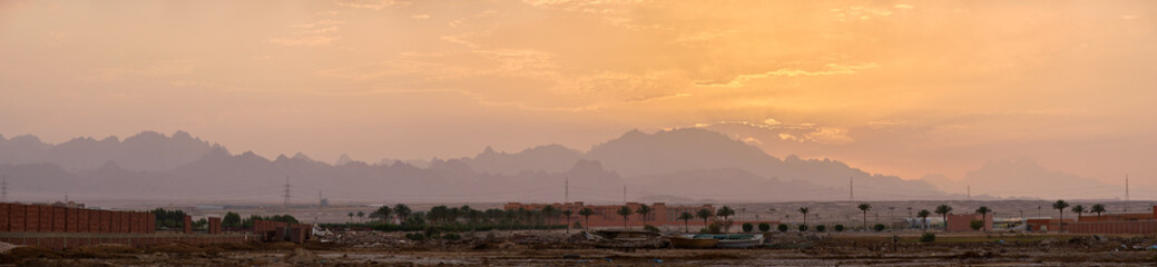 Sunset landscape with remote hotel complex against dark mountain peaks in egyptian desert