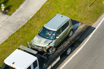 Tow truck hauling smashed vehicle on car accident site. Emergency services responding to traffic crash on American street. First responders helping on road in the USA