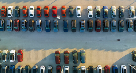 View from above of dealers outdoor parking lot with many brand new cars in stock for sale. Concept of development of american automotive industry