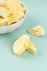 Golden Dried Durian Fruit Slices in Bowl on Mint Background - Tropical Dehydrated Snack