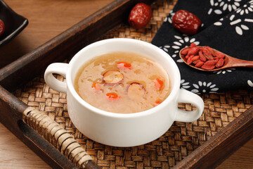 Traditional Asian mushroom vegetable soup with red dates and goji berries on rustic wooden serving tray