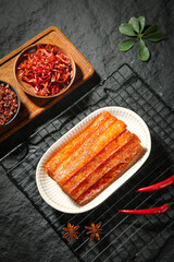 Handmade Spiced Beef Jerky Chorizo Strips with Dried Chili Peppers and Star Anise on Dark Slate Background