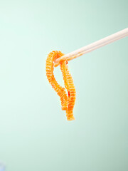 Spicy Konjac Tripe Strips with Chopsticks - Healthy Vegetarian Asian Snack Food on Green Background