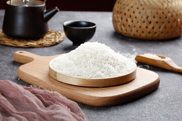 Fresh White Rice Grains on Wooden Board with Traditional Asian Kitchen Utensils and Bamboo Steamer