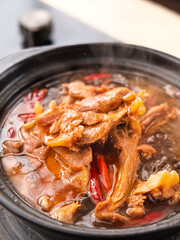 Spicy marinated duck neck stew with peppers in traditional black pot - Asian cuisine comfort food