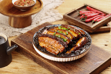 Traditional Chinese braised pork belly with dried plum vegetables and chili peppers on wooden serving board