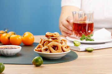 Spicy squid rings seafood appetizer with tea and fresh fruits on wooden table