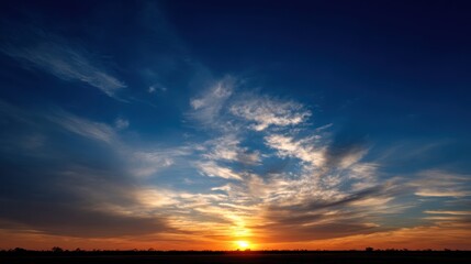 Obraz premium Tranquil golden-orange sunset with illuminated clouds, deep blue sky gradient, wispy formations, expansive plain landscape