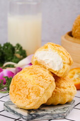 Delicious Cream Puff Pastries with White Filling and Milk on Marble Board