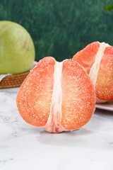 Fresh Thai Ruby Red Pomelo Citrus Fruit Cut Half Showing Pink Flesh Segments on Marble Counter