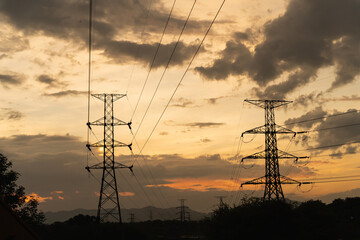 Silhouetted Power Lines Against a Dramatic Sunset Sky with Cloudy Atmosphere and Mountains in the Background Capturing Nature's Beauty