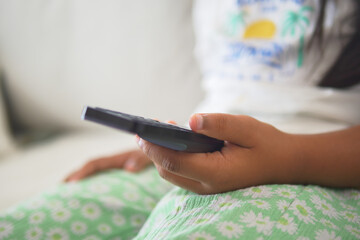 Child holding a remote on the couch at home in summer