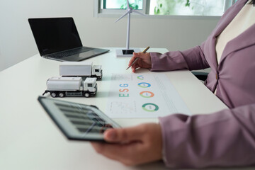 ESG Strategy. Businesswoman reviewing sustainability data with model trucks.