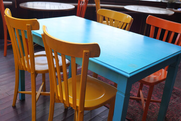 Colorful chairs around a blue table in a cozy cafe