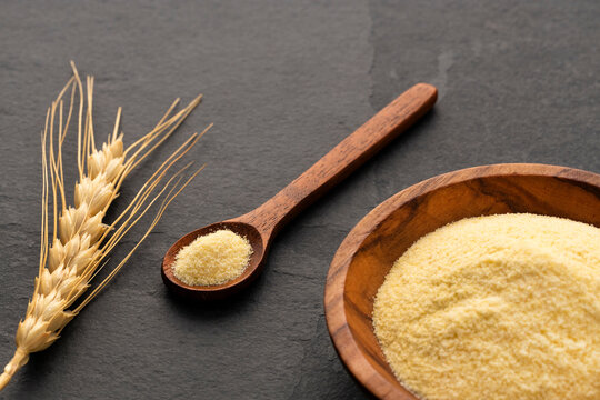 Coarse wheat semolina flour in a bowl and wooden spoon - Triticum