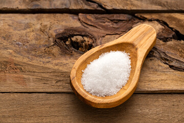 Fine crystals of refined white sugar on a wooden spoon - Saccharum officinarum