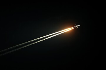Jet plane soaring through dark night sky, trails of light