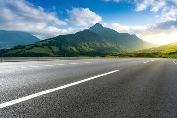 Fototapeta premium Open asphalt road stretching towards distant mountains under a clear blue sky on a sunny day offering travel freedom.