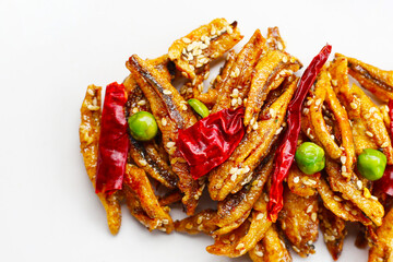 Crispy fried anchovies with sesame, dried chili, green peas, and herbs on white background.