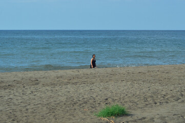A young girl walks with wet clothes from the ocean back to the sandy shore, enjoying the casual tropical beachside under bright natural daylight.
