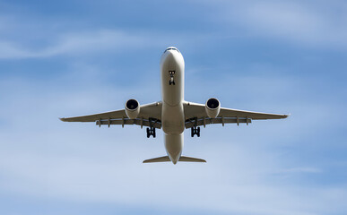 Obraz premium White Passenger Jet Plane Two Engine Front View Low Angle Flying Over Blue Sky